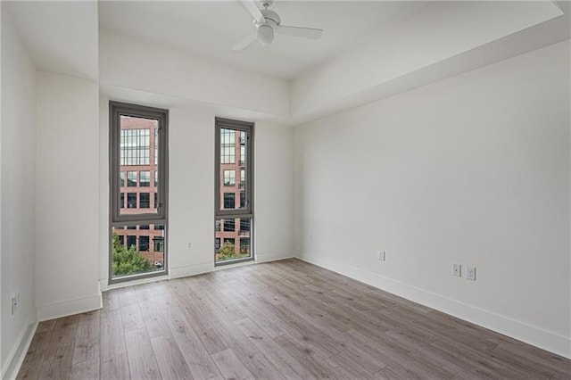 unfurnished room with a tray ceiling, light hardwood / wood-style flooring, and ceiling fan