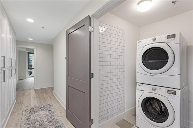 laundry room with stacked washer / drying machine and light hardwood / wood-style floors