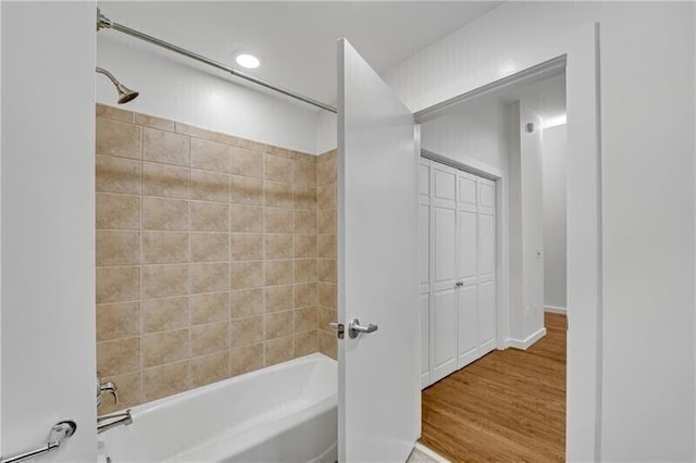 bathroom with hardwood / wood-style flooring and tiled shower / bath