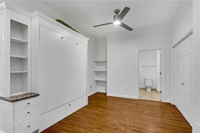 unfurnished bedroom featuring ceiling fan, dark hardwood / wood-style floors, and connected bathroom