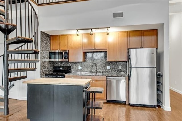 kitchen with light hardwood / wood-style floors, butcher block counters, sink, and appliances with stainless steel finishes