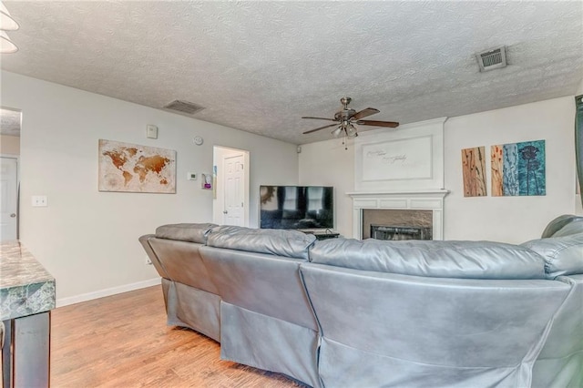 3623 Thurleston Ct SW, Marietta, GA 30008 - living room featuring a ceiling fan, light wood finished floors, a fireplace, and a textured ceiling
