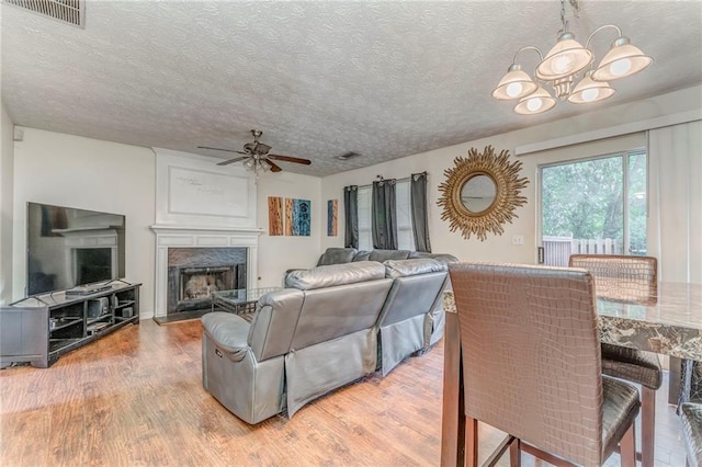 3623 Thurleston Ct SW, Marietta, GA 30008 - living room with a ceiling fan, a chandelier, light wood-style flooring, a premium fireplace, and a textured ceiling