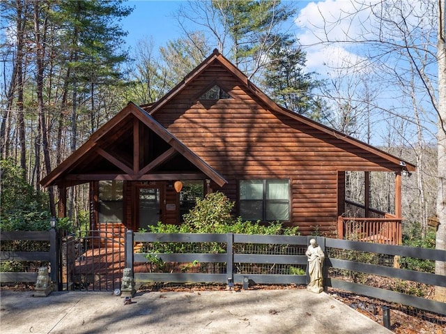 chalet / cabin with a gate, faux log siding, and a fenced front yard