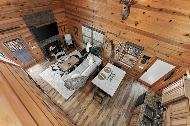 living room with wooden walls, wood finished floors, and a lit fireplace