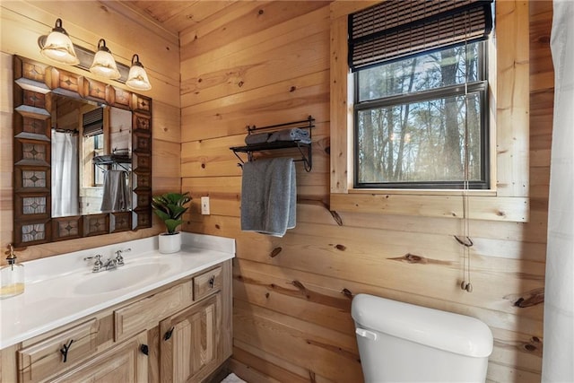 bathroom featuring toilet, a shower with curtain, wood walls, and vanity