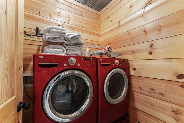 washroom with wood walls, washing machine and clothes dryer, and laundry area