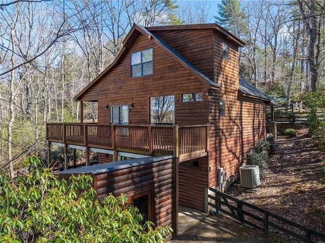 rear view of property featuring central air condition unit, faux log siding, and a wooden deck