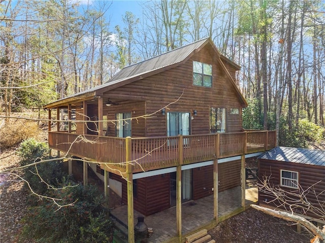 view of property exterior with a deck, a ceiling fan, log veneer siding, and metal roof