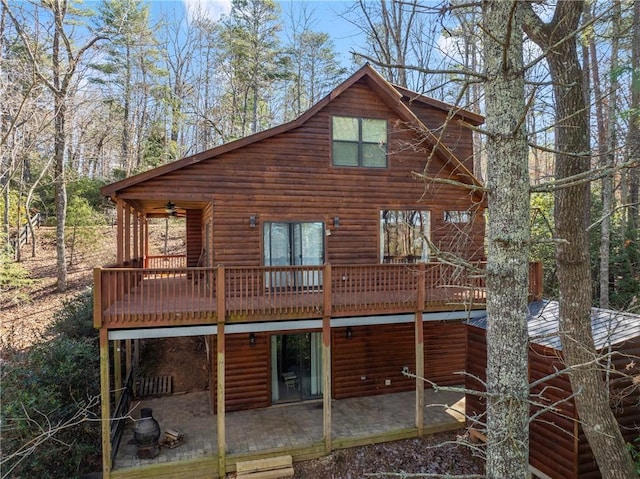 rear view of property with a deck, faux log siding, ceiling fan, and a patio area