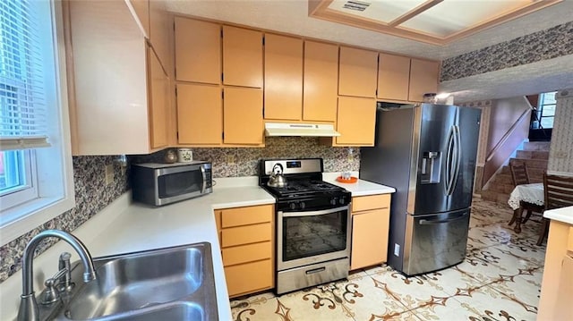 kitchen with appliances with stainless steel finishes, sink, tasteful backsplash, and light tile floors