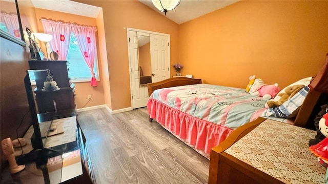 bedroom featuring vaulted ceiling, hardwood / wood-style floors, and a closet