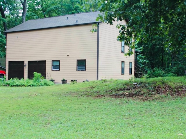 view of side of home featuring a garage and a lawn