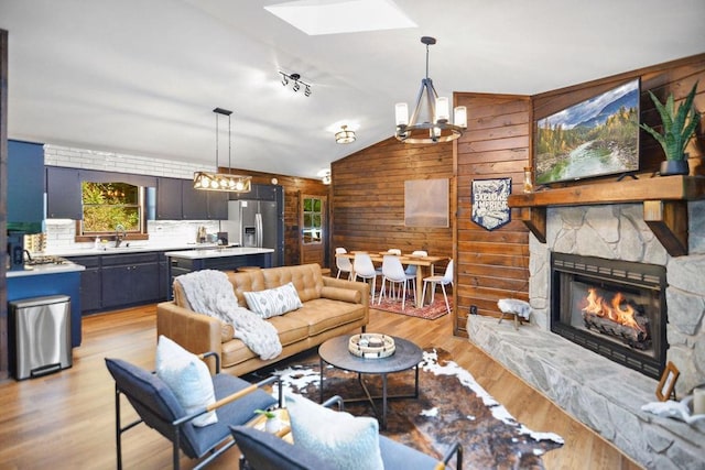 307 Pigeon Creek Rd, Blue Ridge, GA 30513 - living room featuring wooden walls, a skylight, lofted ceiling, light wood-style floors, and a stone fireplace