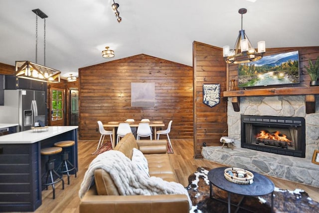 307 Pigeon Creek Rd, Blue Ridge, GA 30513 - living area with a chandelier, wooden walls, lofted ceiling, light wood-style flooring, and a stone fireplace