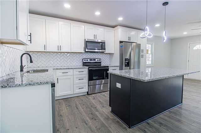 kitchen with white cabinetry, decorative light fixtures, a kitchen island, and appliances with stainless steel finishes