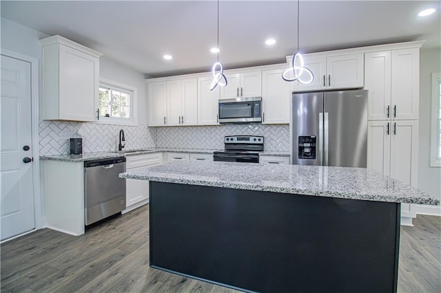 kitchen featuring appliances with stainless steel finishes, decorative light fixtures, sink, white cabinets, and a center island