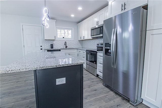 kitchen with sink, white cabinetry, a center island, hanging light fixtures, and appliances with stainless steel finishes