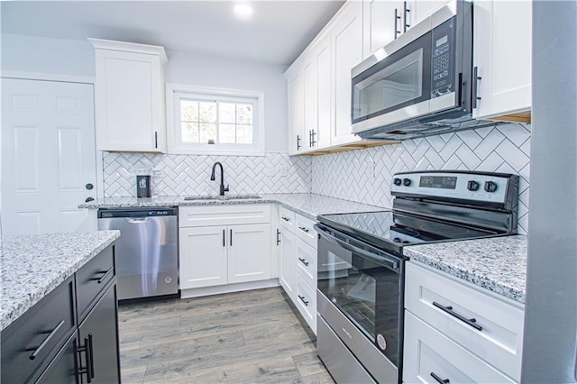 kitchen featuring white cabinetry, appliances with stainless steel finishes, light stone countertops, and sink