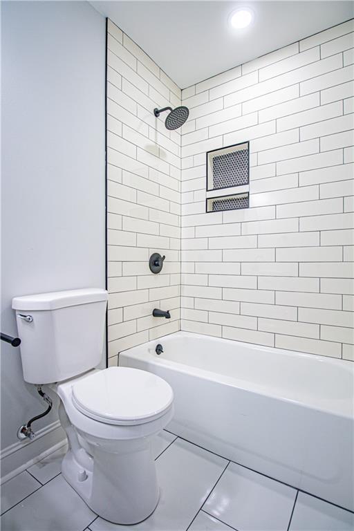 bathroom featuring toilet and tiled shower / bath combo