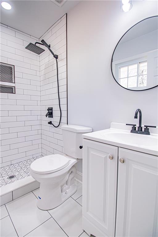 bathroom with vanity, a tile shower, and toilet