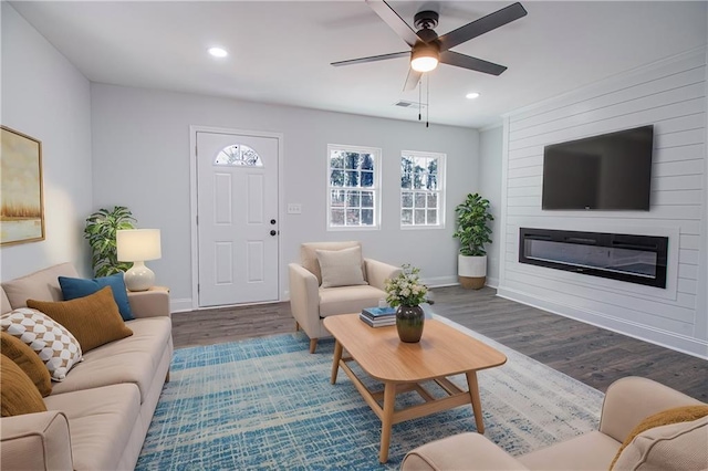 living room with dark hardwood / wood-style flooring, a fireplace, and ceiling fan