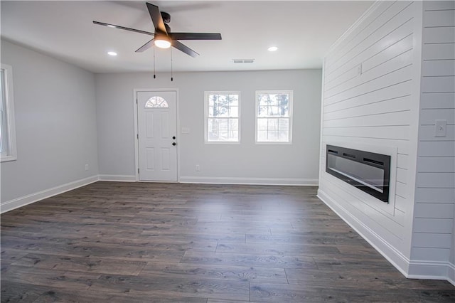 entrance foyer with dark wood-type flooring, a large fireplace, and ceiling fan