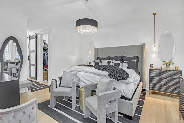 bedroom with wood-type flooring, a barn door, and ornamental molding