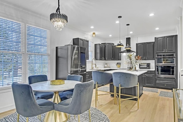 kitchen featuring a center island, hanging light fixtures, island exhaust hood, light hardwood / wood-style floors, and appliances with stainless steel finishes