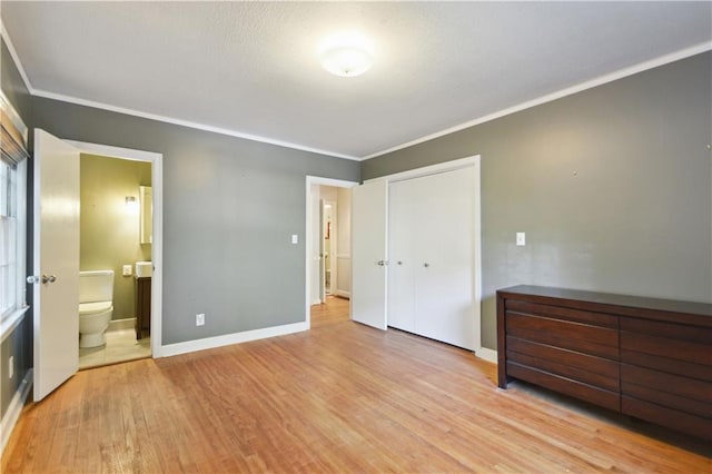 unfurnished bedroom featuring crown molding, a closet, connected bathroom, wood finished floors, and baseboards