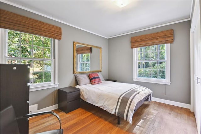 bedroom featuring ornamental molding, baseboards, and wood finished floors