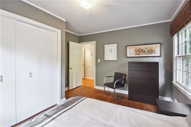 bedroom featuring ornamental molding, a closet, wood finished floors, and baseboards