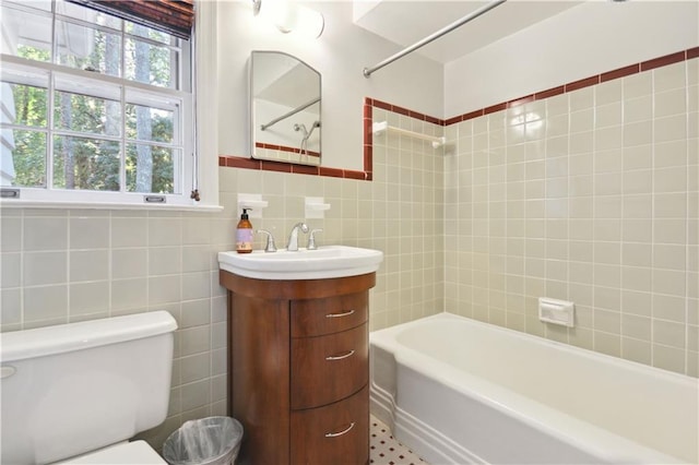 full bath featuring toilet, tub / shower combination, vanity, and tile walls