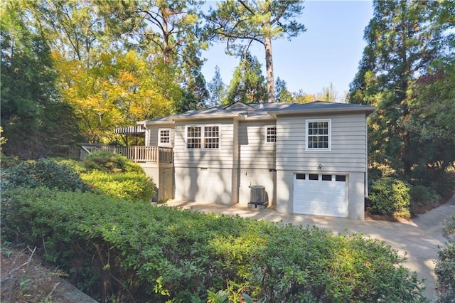 exterior space featuring central air condition unit, a garage, and concrete driveway