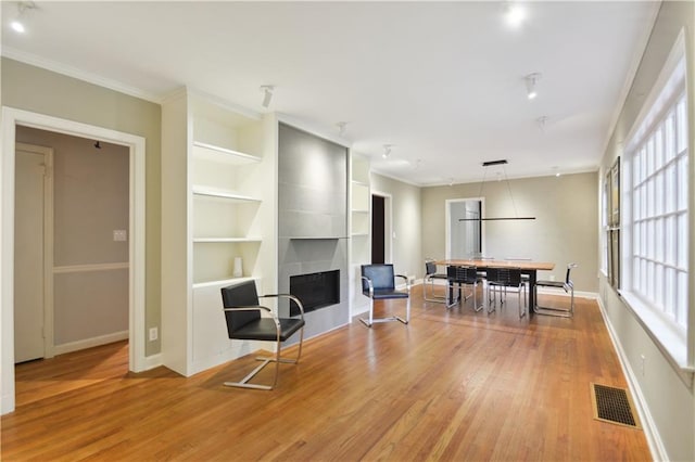 interior space with a large fireplace, wood finished floors, visible vents, and baseboards