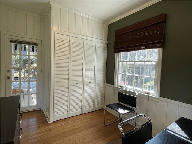 bedroom with a closet, wainscoting, light wood-style flooring, and crown molding