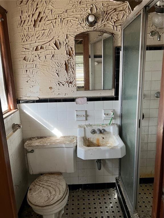 bathroom with tile patterned floors, toilet, tile walls, and sink