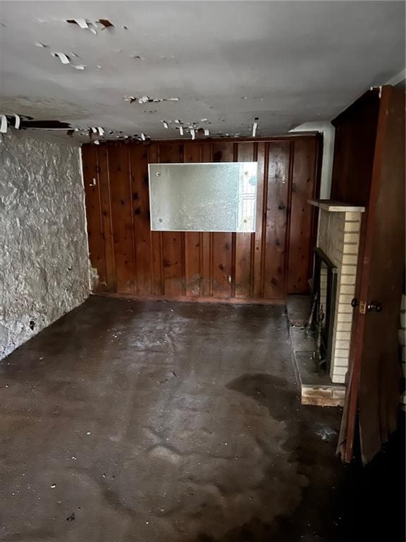 basement featuring a brick fireplace and wood walls