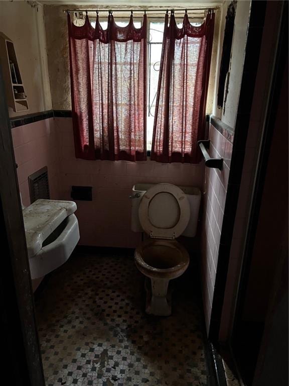 bathroom featuring toilet and tile walls