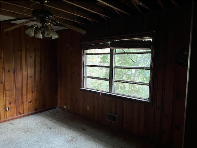 spare room featuring ceiling fan and wood walls