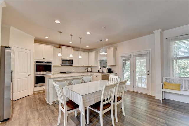 dining space with crown molding, sink, and light hardwood / wood-style flooring