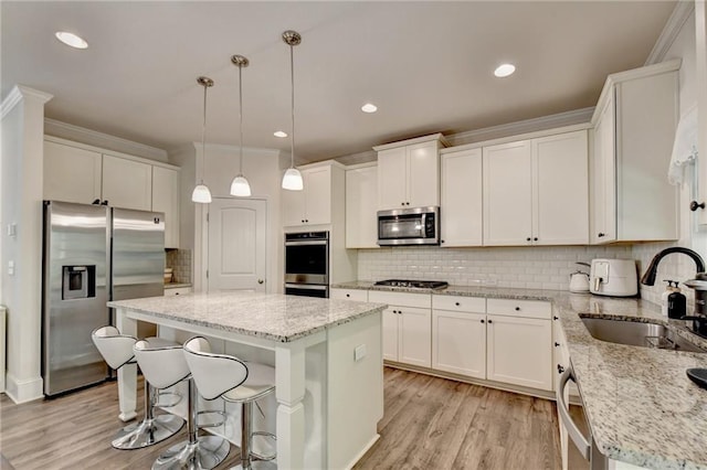 kitchen featuring hanging light fixtures, sink, a kitchen island, appliances with stainless steel finishes, and light stone countertops