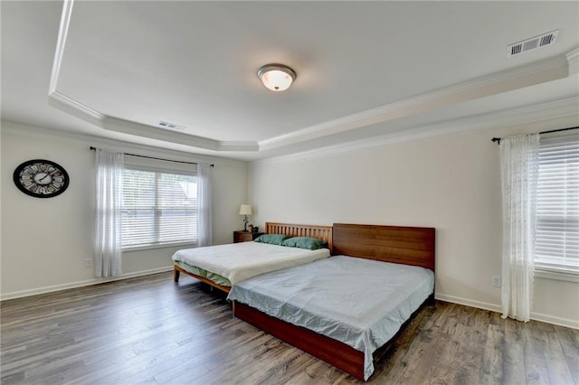 bedroom featuring a tray ceiling, hardwood / wood-style flooring, and crown molding