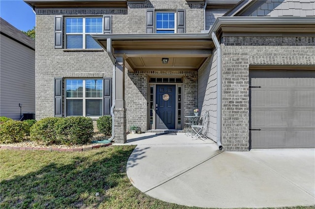 view of exterior entry with a lawn, cooling unit, and a garage