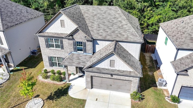 view of front of home with a garage, central AC unit, and a front lawn