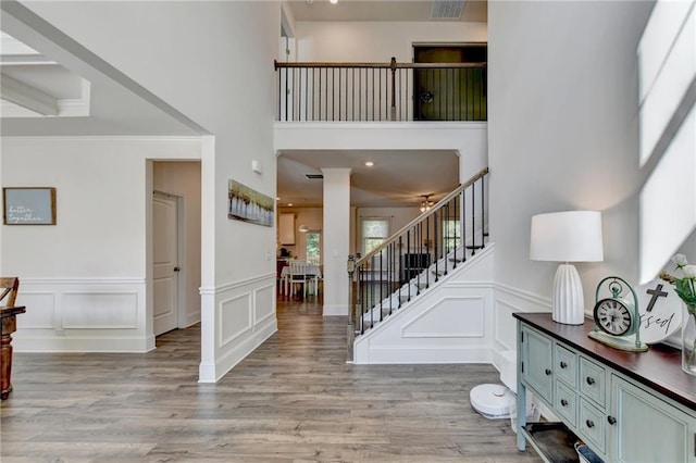 entryway with light hardwood / wood-style flooring, a towering ceiling, and ornate columns