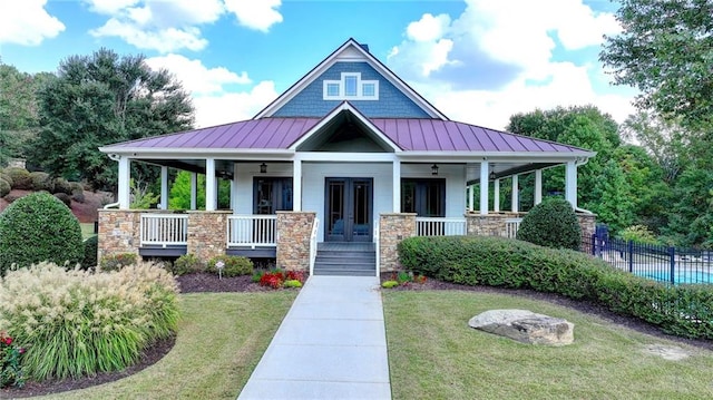 view of front of house featuring french doors, ceiling fan, a front lawn, and covered porch