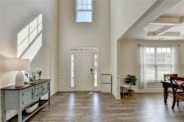 foyer entrance with a towering ceiling, beamed ceiling, coffered ceiling, dark hardwood / wood-style floors, and crown molding