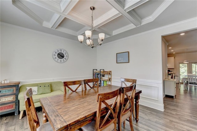 dining room featuring light hardwood / wood-style floors, a notable chandelier, beam ceiling, coffered ceiling, and crown molding