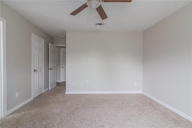 carpeted empty room with ceiling fan, visible vents, and baseboards